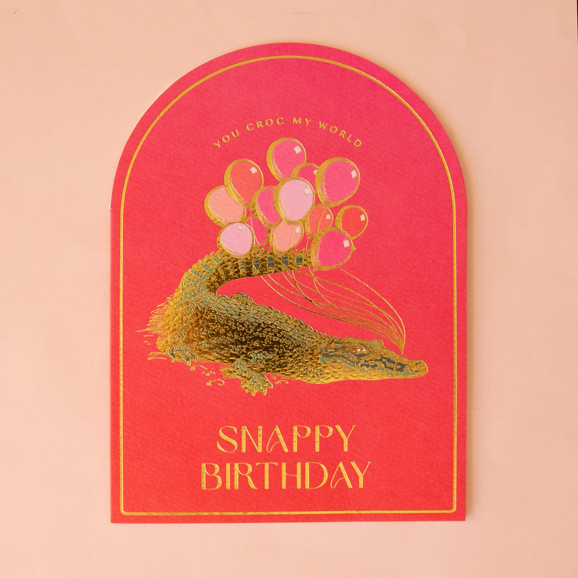 hot pink greeting card with gold foil illustration of crocodile. text reads snappy birthday