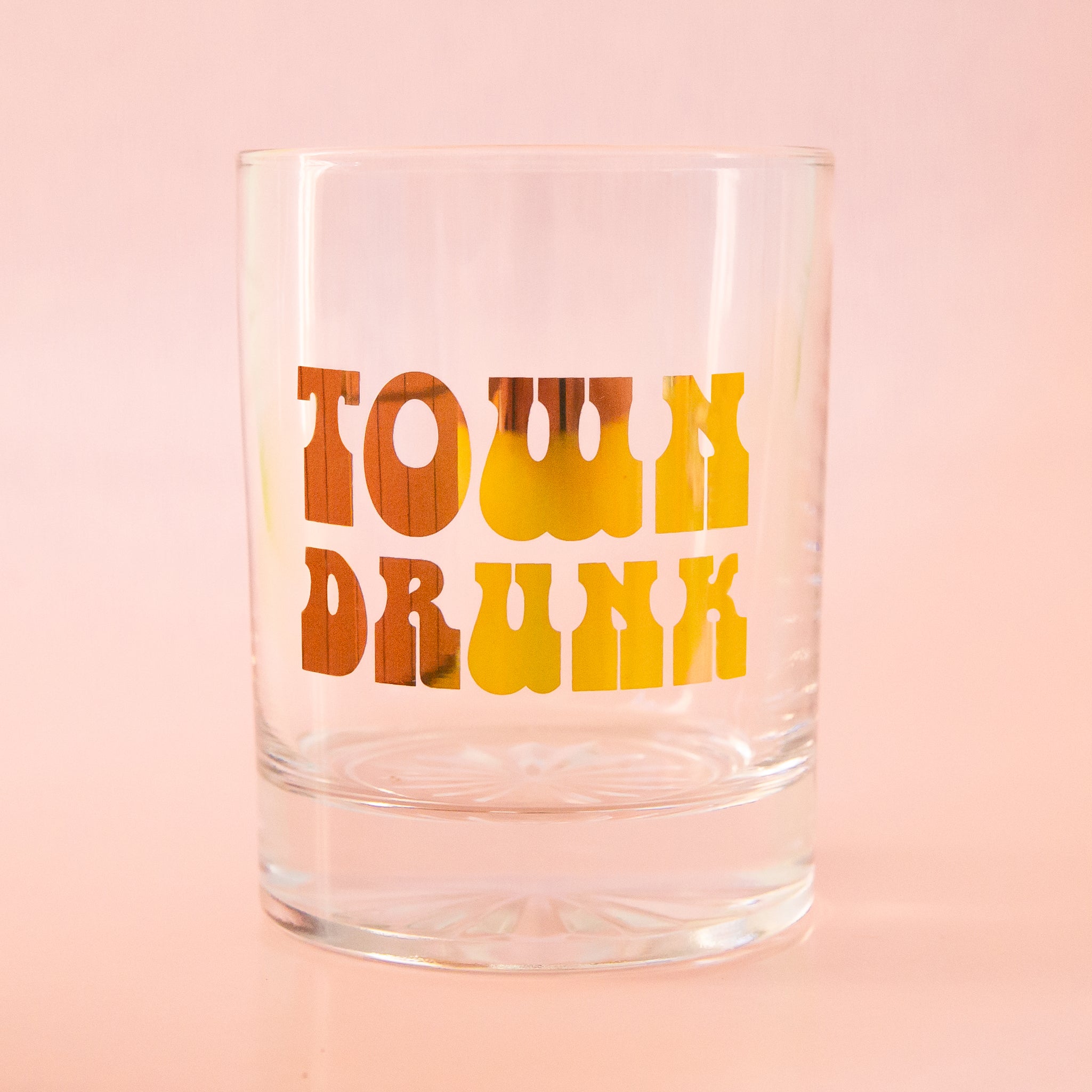 A glass tumbler with gold text that reads, 'Town Drunk'. 