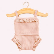 A rib knit tank top and shorts set in light pink color with lace detailing on the top and the sides of the shorts.   The outfit is hanging on a small wooden hanger.