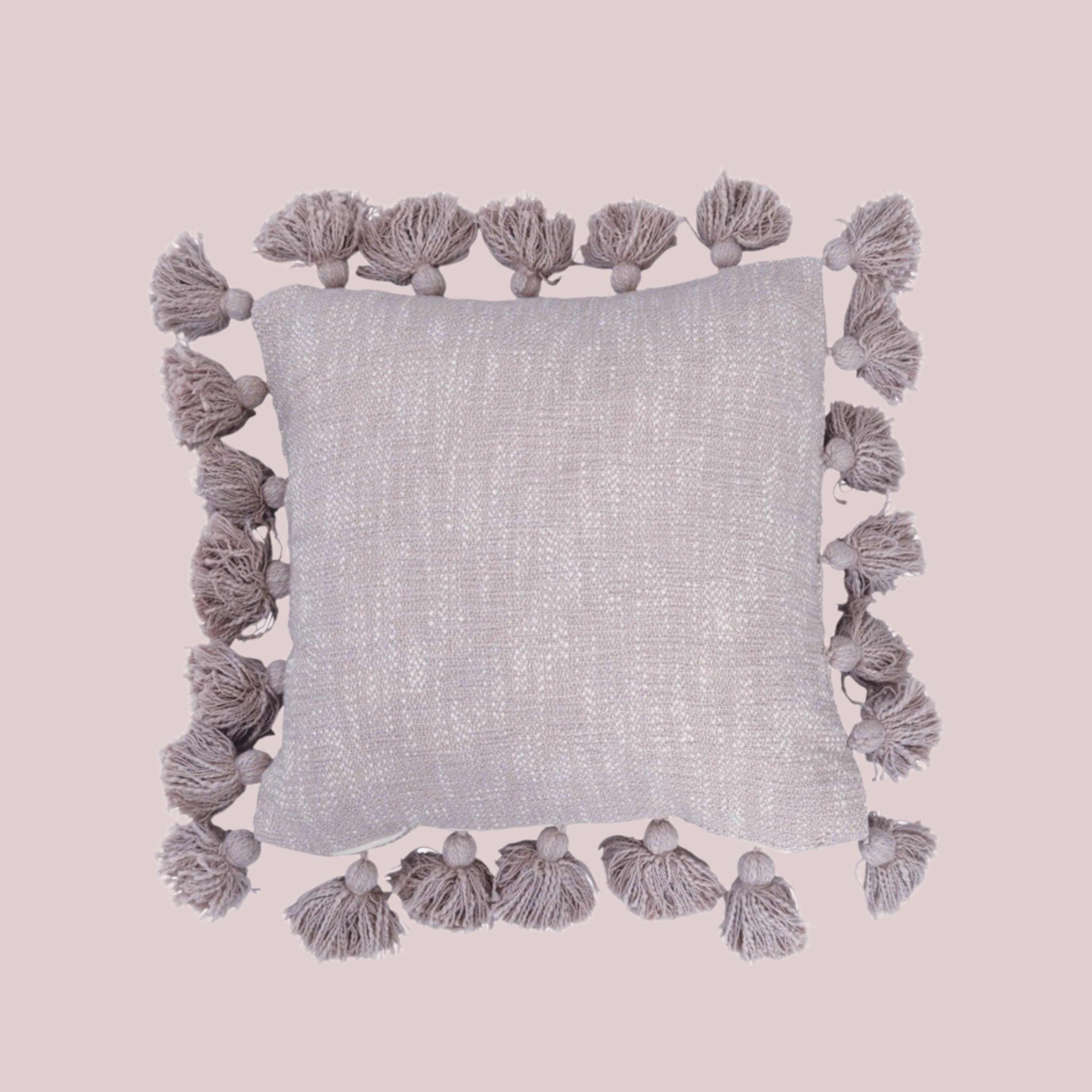 A light lavender colored throw pillow with tassels around the edge. 