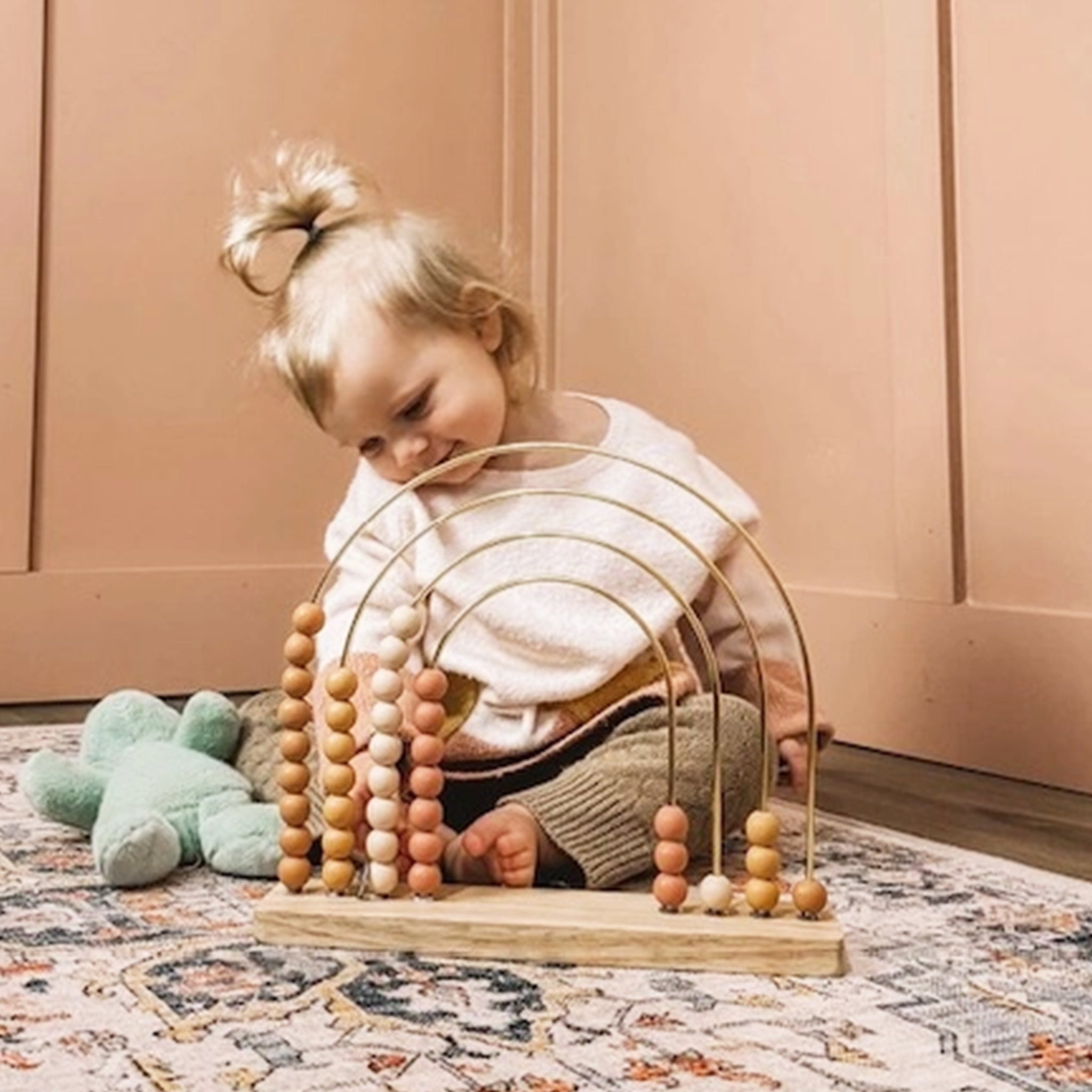 A wire and wood bead abacus toy in mauve tones.