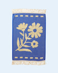 A blue hand towel with a cream floral print design and fringe details on each end. 