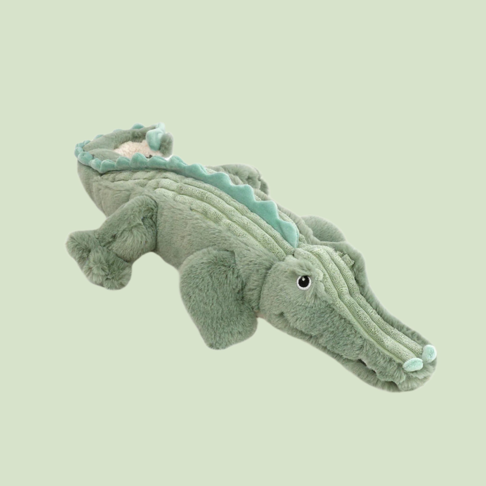 A light green alligator shaped stuffed animal. 