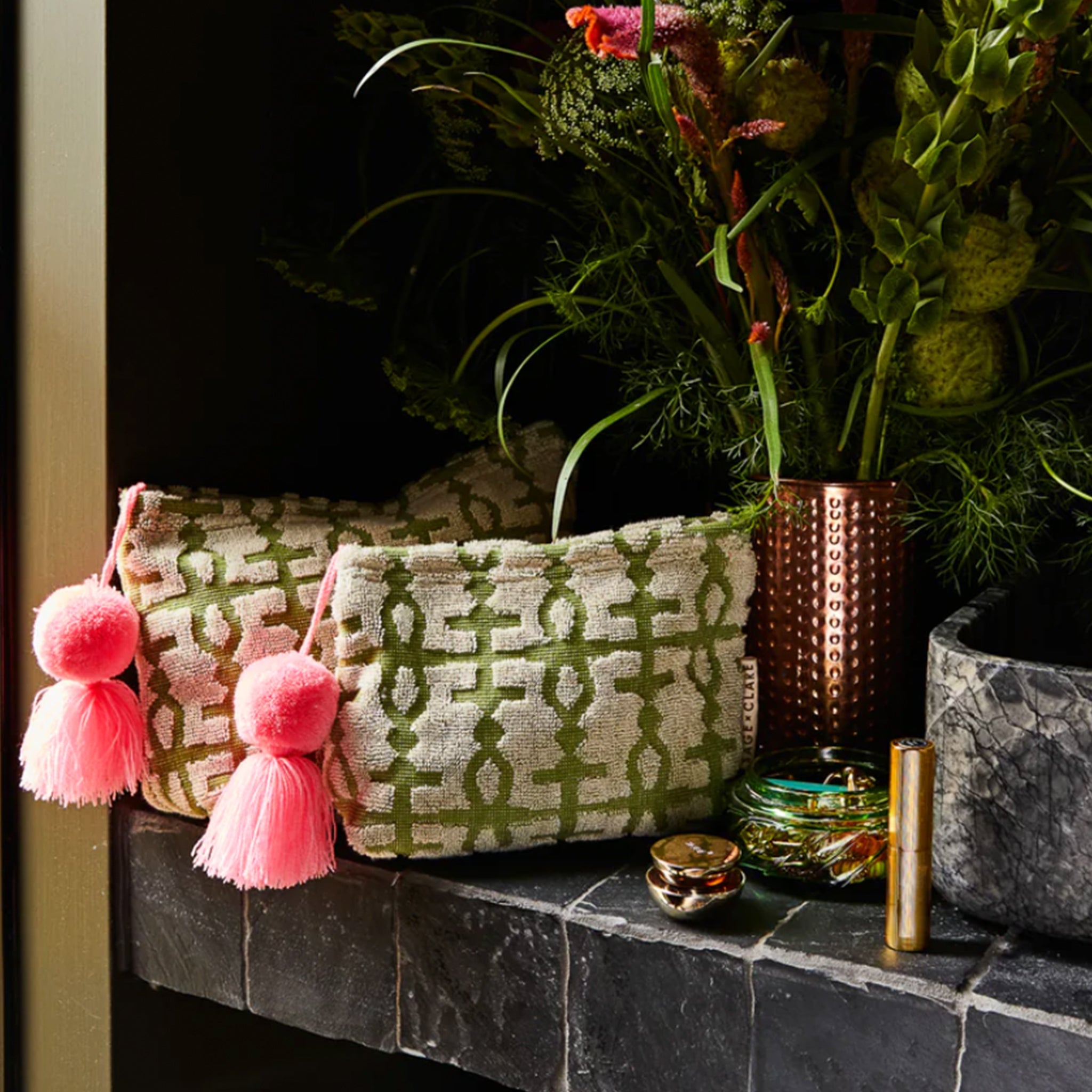 A green and ivory terry cloth pouch with a pink tassel. 