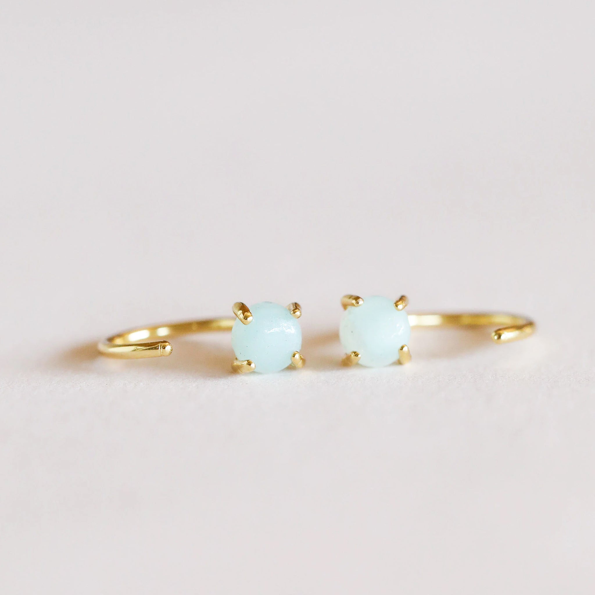 Gold huggie style earrings with set aqua colored amazonite gem.