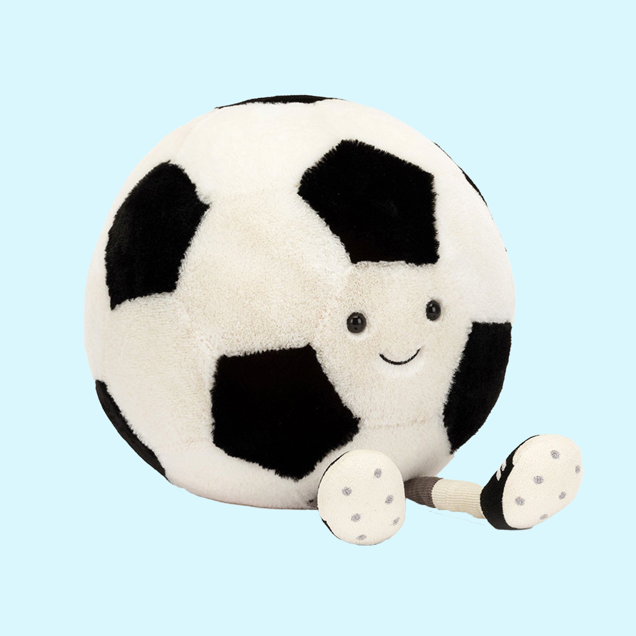 On a blue background is a black and white soccer ball stuffed toy. 