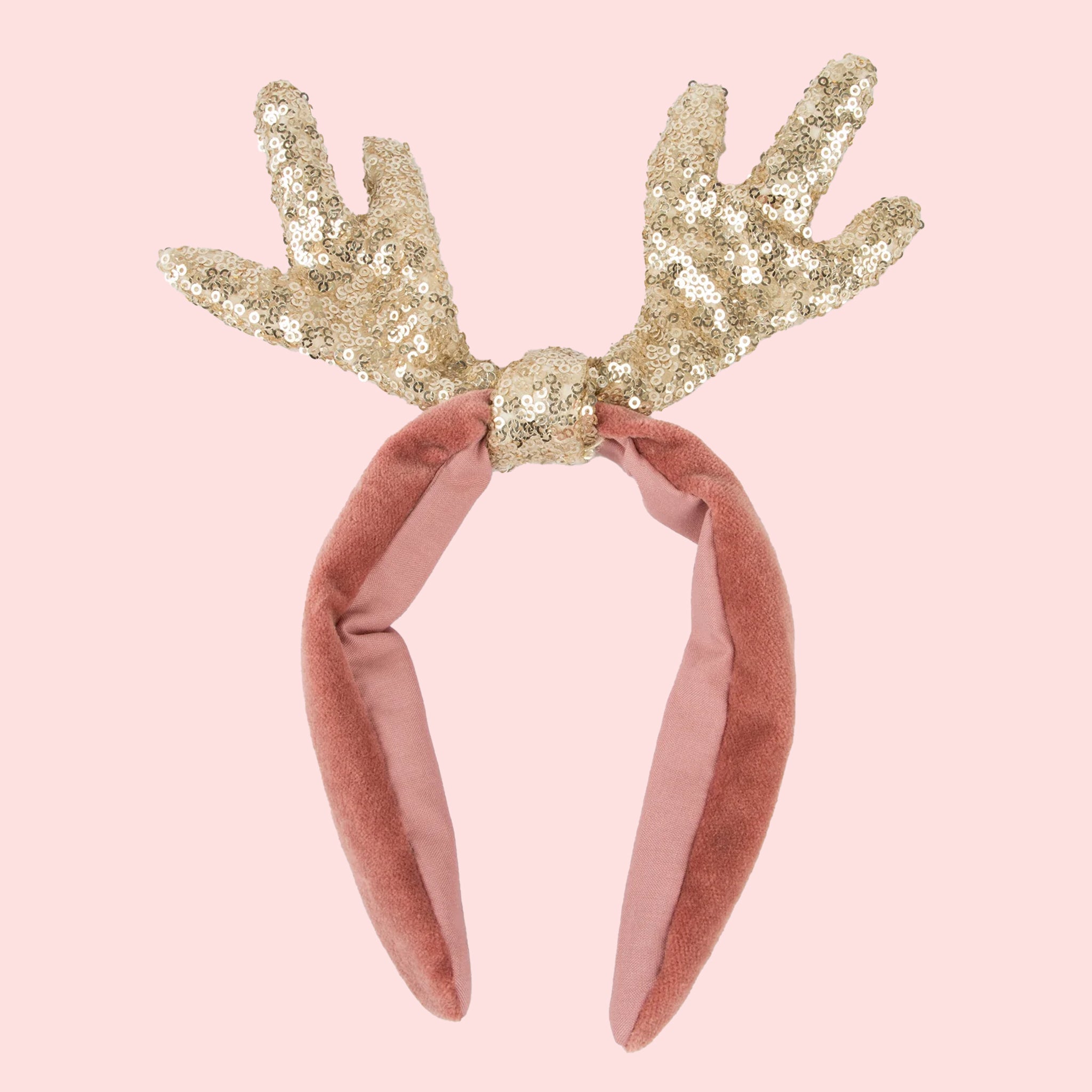 A pink velvet headband with sequin antler top.