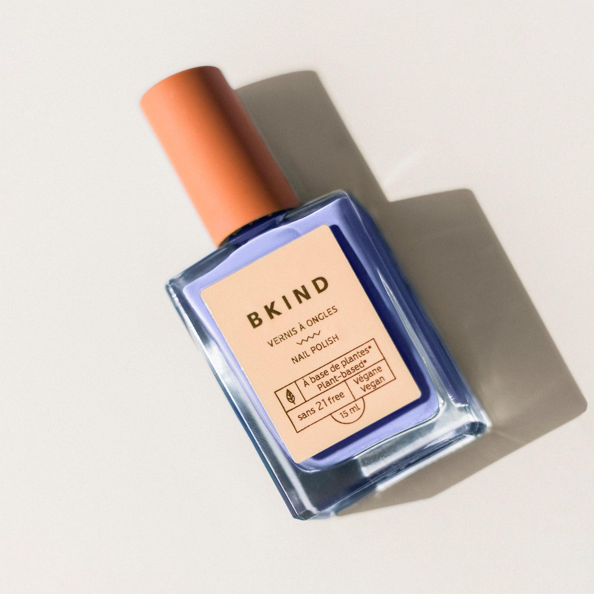 A lilac blue nail polish bottle with a peachy screw on top. 