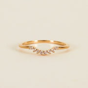 On a tan background is a gold ring with small cubic zirconias along the small dip. 