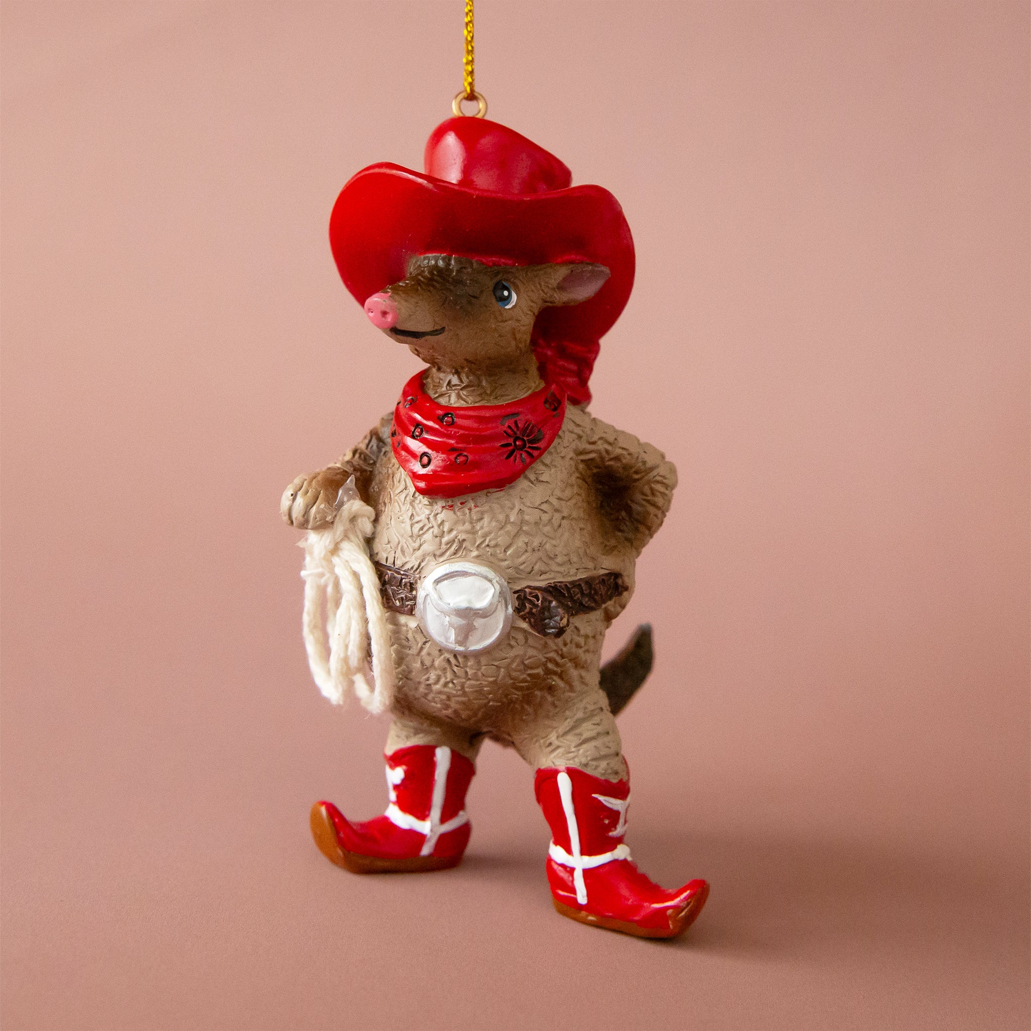 A brown resin armadillo shaped ornament dressed in a red western outfit. 