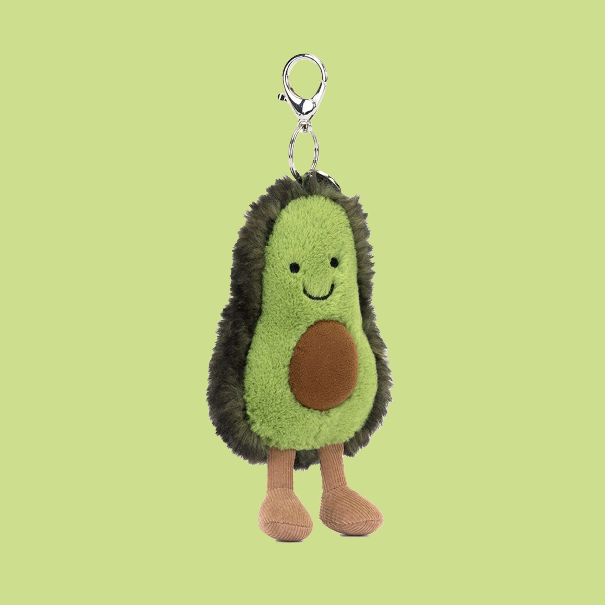 A bag charm in the shape of a stuffed toy avocado with silver details. 