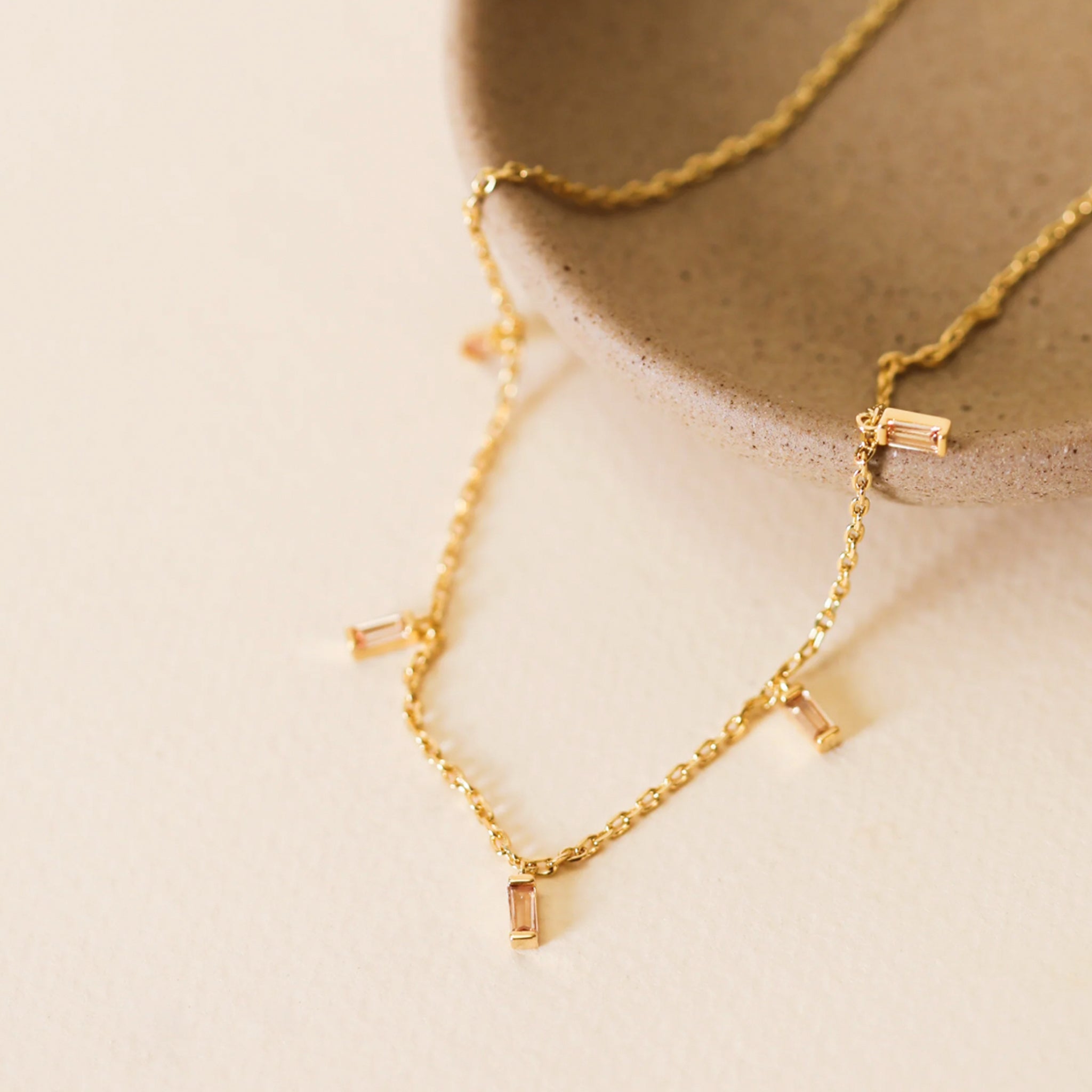 A gold necklace with baguette stones placed along the chain. 