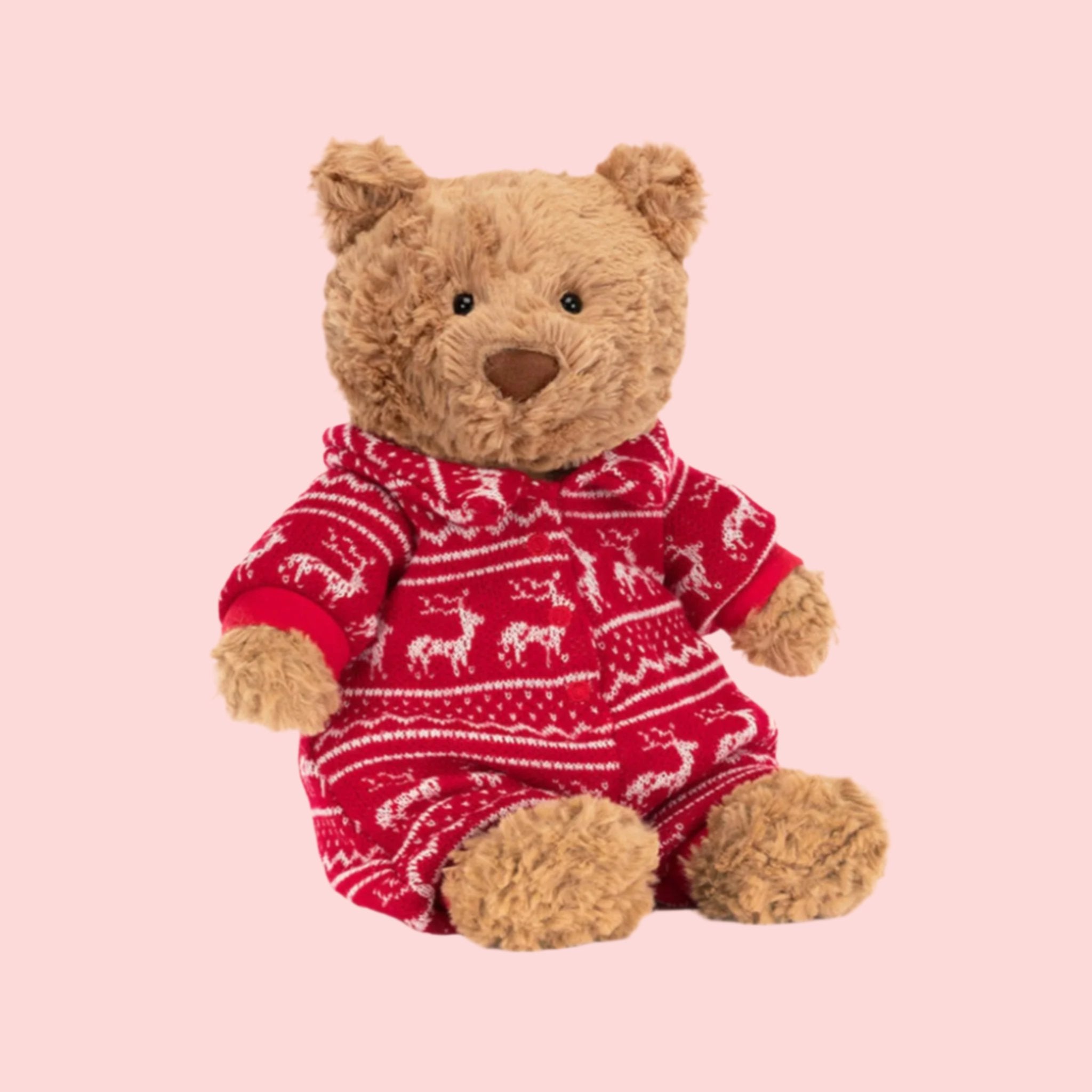 A brown bear stuffed animal wearing a red winter pajama onesie. 