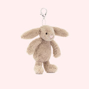 A beige bunny stuffed toy on a silver keychain. 