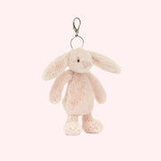 A light pink bunny stuffed toy with a silver keychain. 