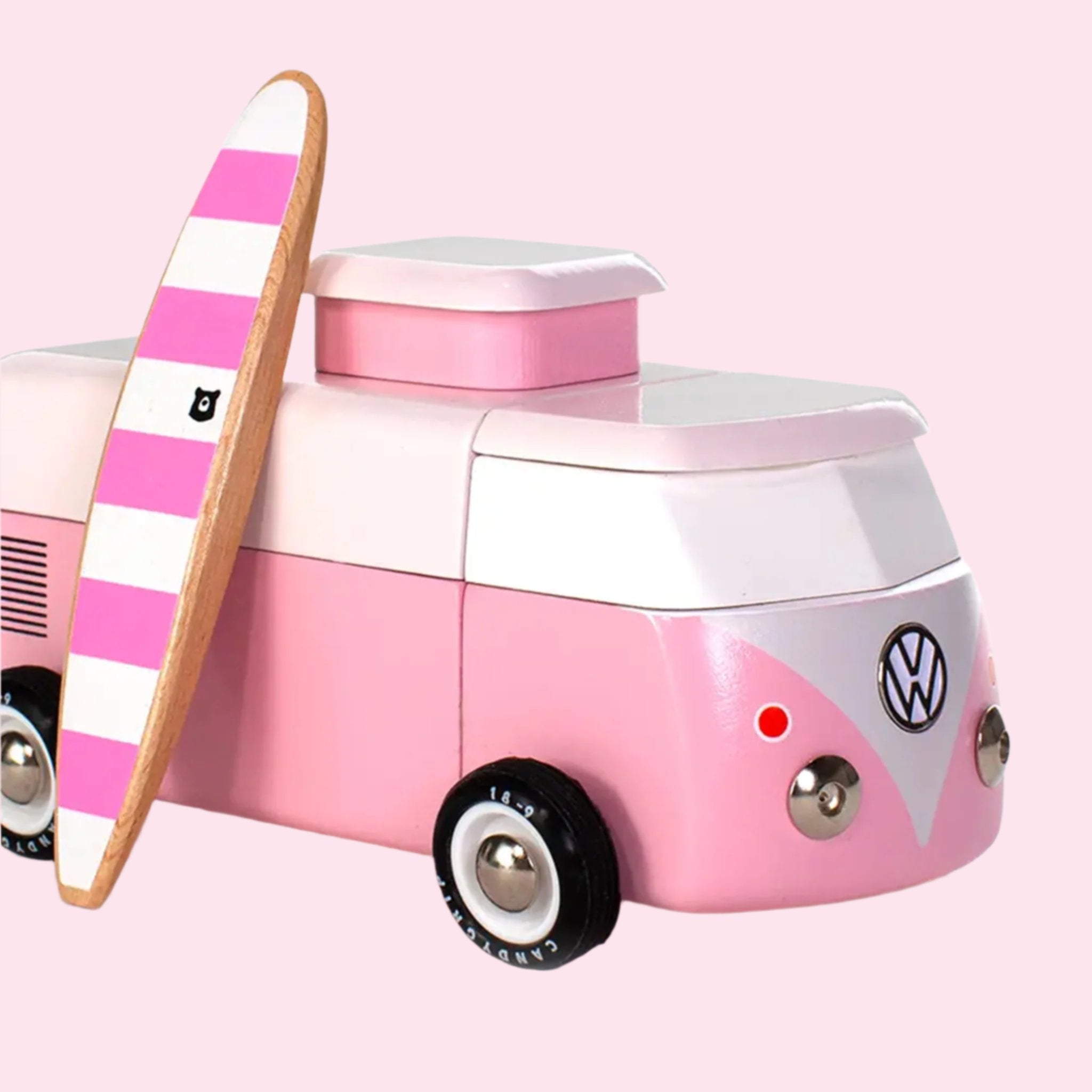 A pink VW wooden toy bus with a magnetic surfboard accessory. 