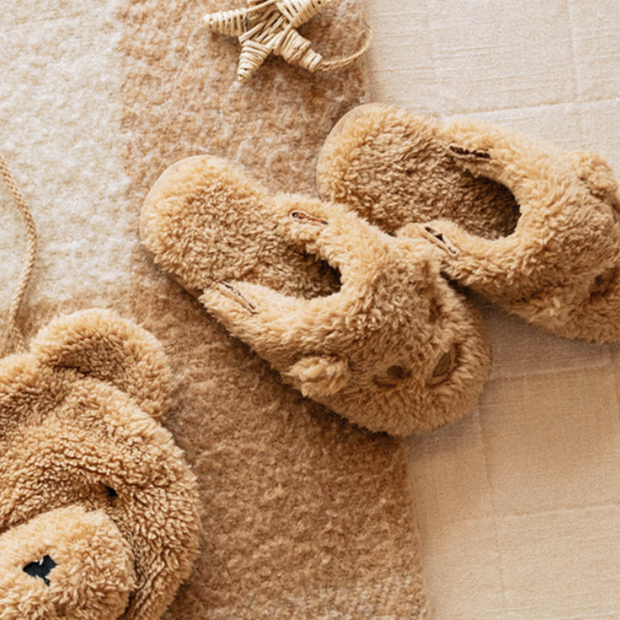 A pair of fuzzy brown slippers with a bear face design on the front. 