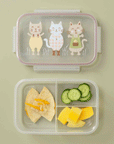 On a green background is a clear plastic bento box with three kitty graphics on the lid filled here with a lunch. 