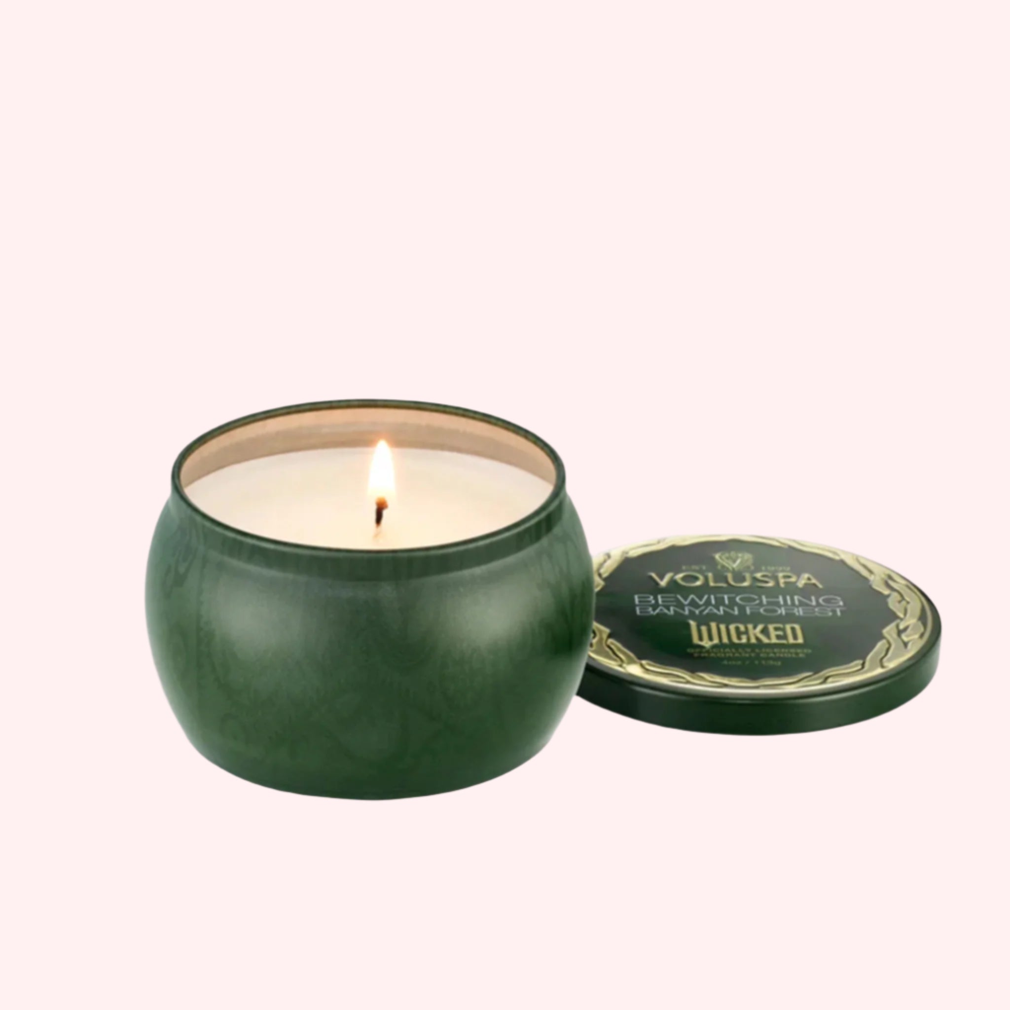 A green tin candle with gold details that reads, &#39;Voluspa, Bewitching Banyan Forest&#39; Wicked. 