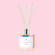 A glass diffuser that's iridescent with wooden reeds and a label that reads, "BFF". 