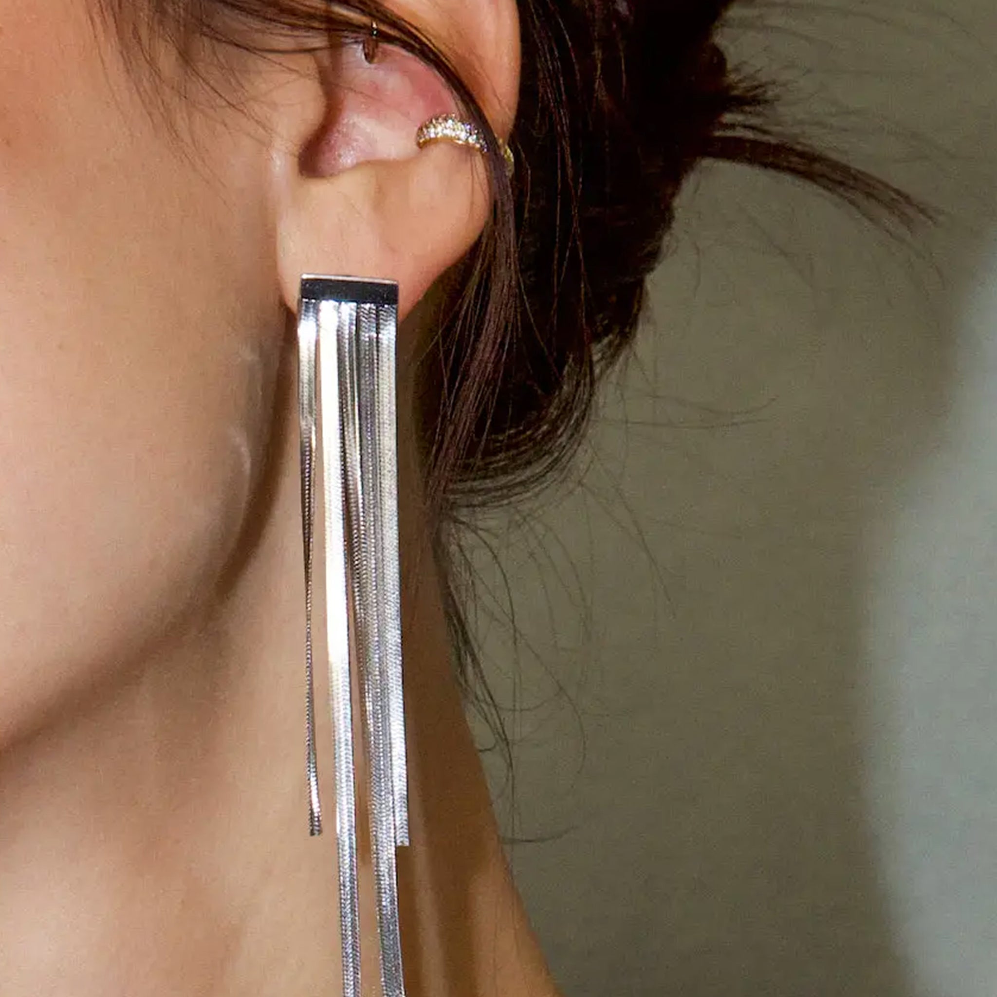 A silver pair of dangle earrings.