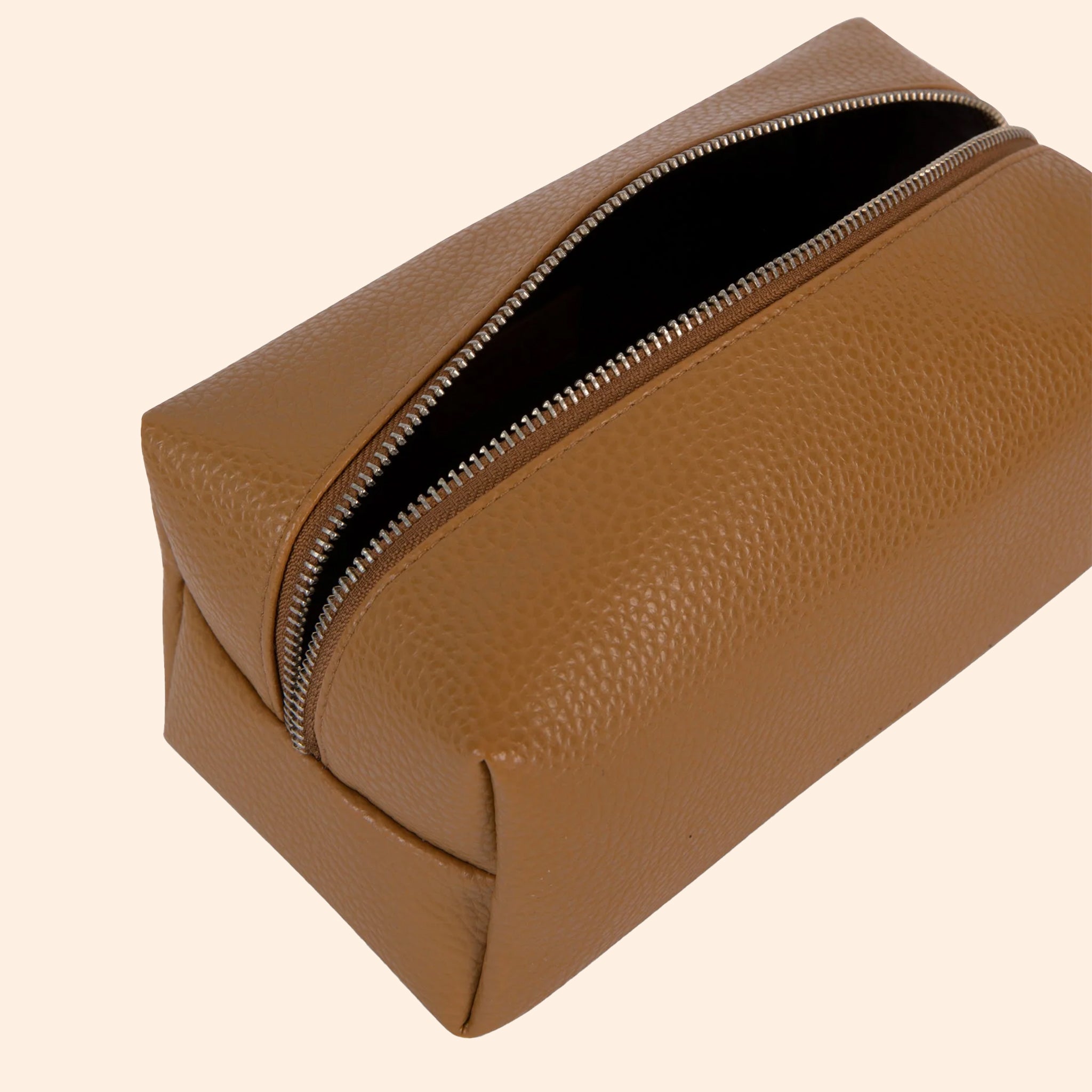 A warm brown vegan leather toiletry / cosmetic bag with a zipper closure and handle on one side. 