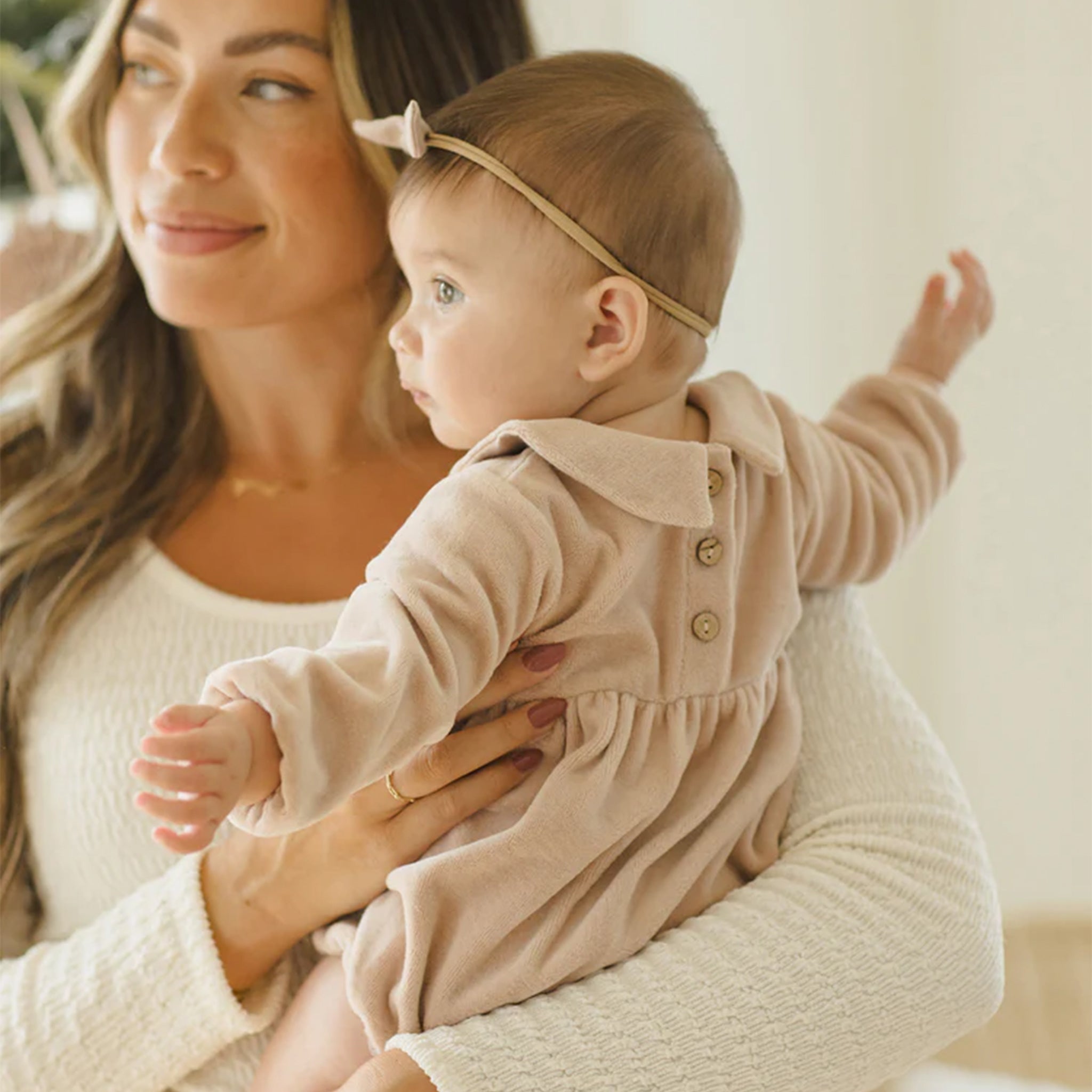 A light blush colored velvet romper with a ruffle collar. 