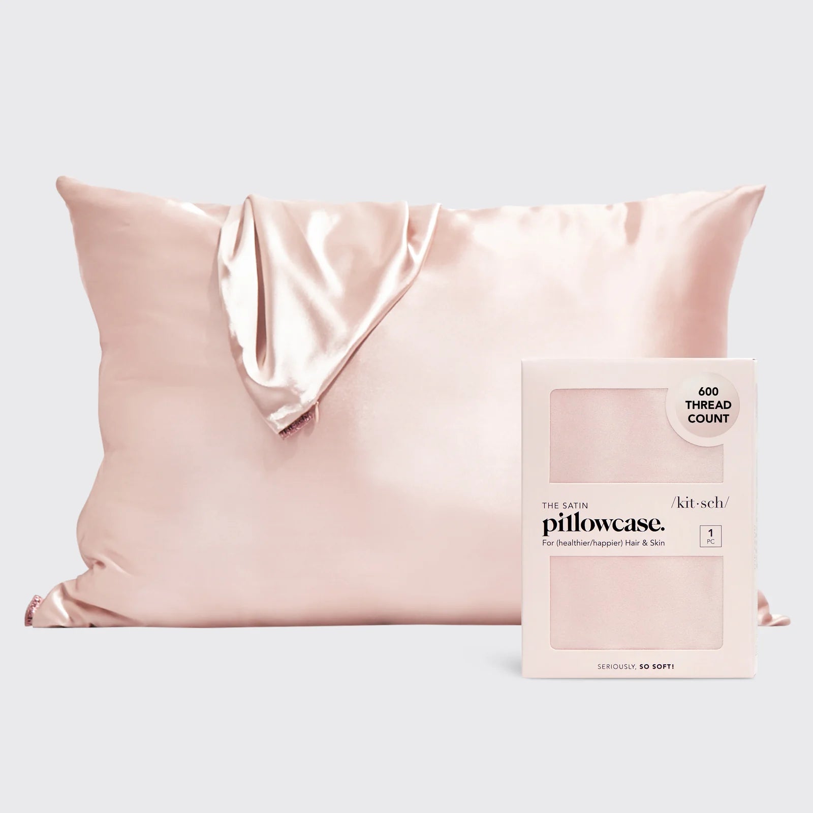 A blush colored satin pillow and an unstuffed blush satin pillowcase resting on top shown behind the product packaging, which includes details like "600 thread count" and "seriously, so soft!.