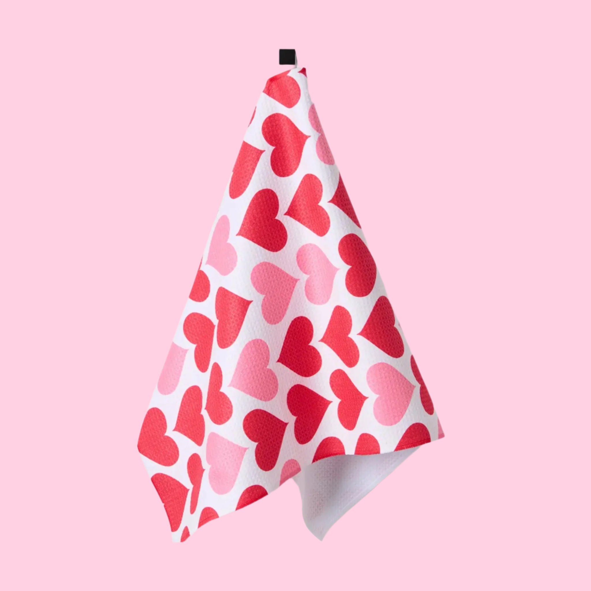 A one side printed waffle knit tea towel with a pink and red heart pattern. 