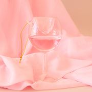 A wine glass ornament features a double lined glass with pink liquid on the inside for some movement!