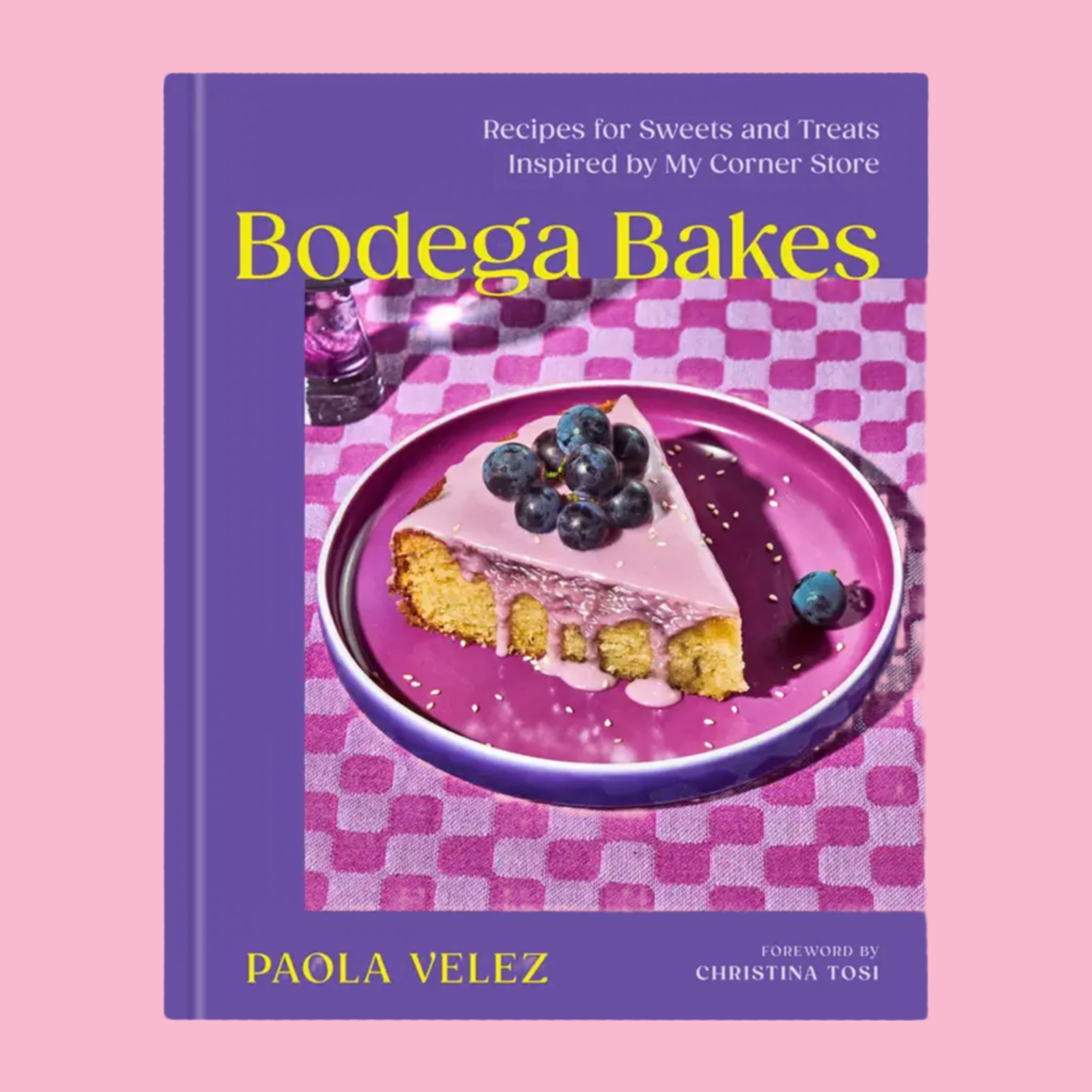 A purple book cover with a photograph of a piece of blueberry cake and the title that reads, 'Bodega Bakes Recipes for Sweets and Treats Inspired by My Corner Store'.