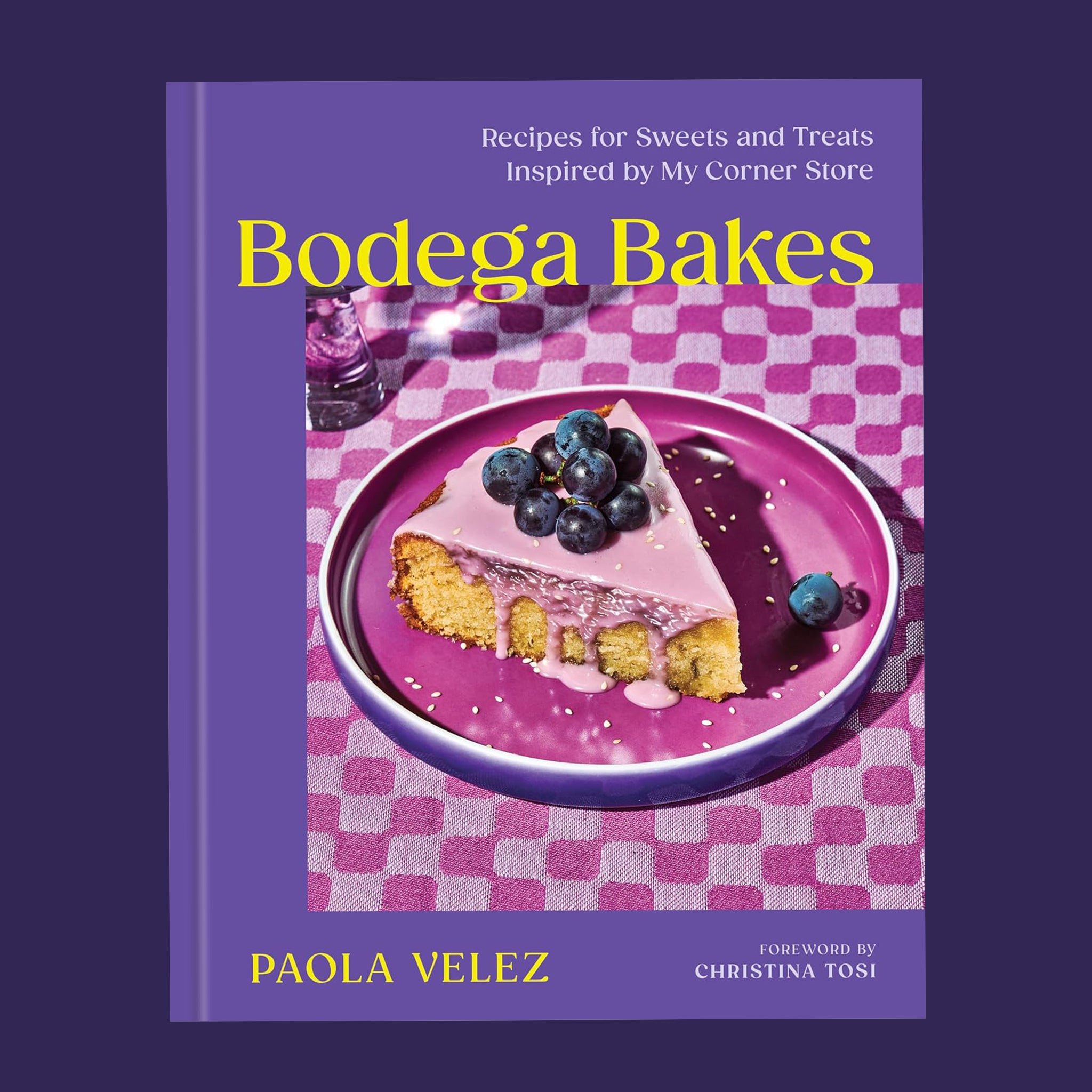 A purple book cover with a photograph of a piece of blueberry cake and the title that reads, 'Bodega Bakes Recipes for Sweets and Treats Inspired by My Corner Store'.