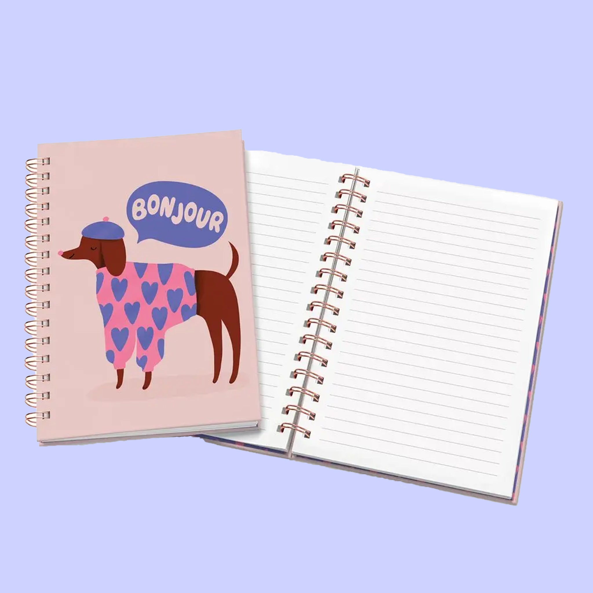 A light pink journal with an illustration of a dog wearing a beret and a speech bubble above that reads, &quot;Bonjour&quot;.