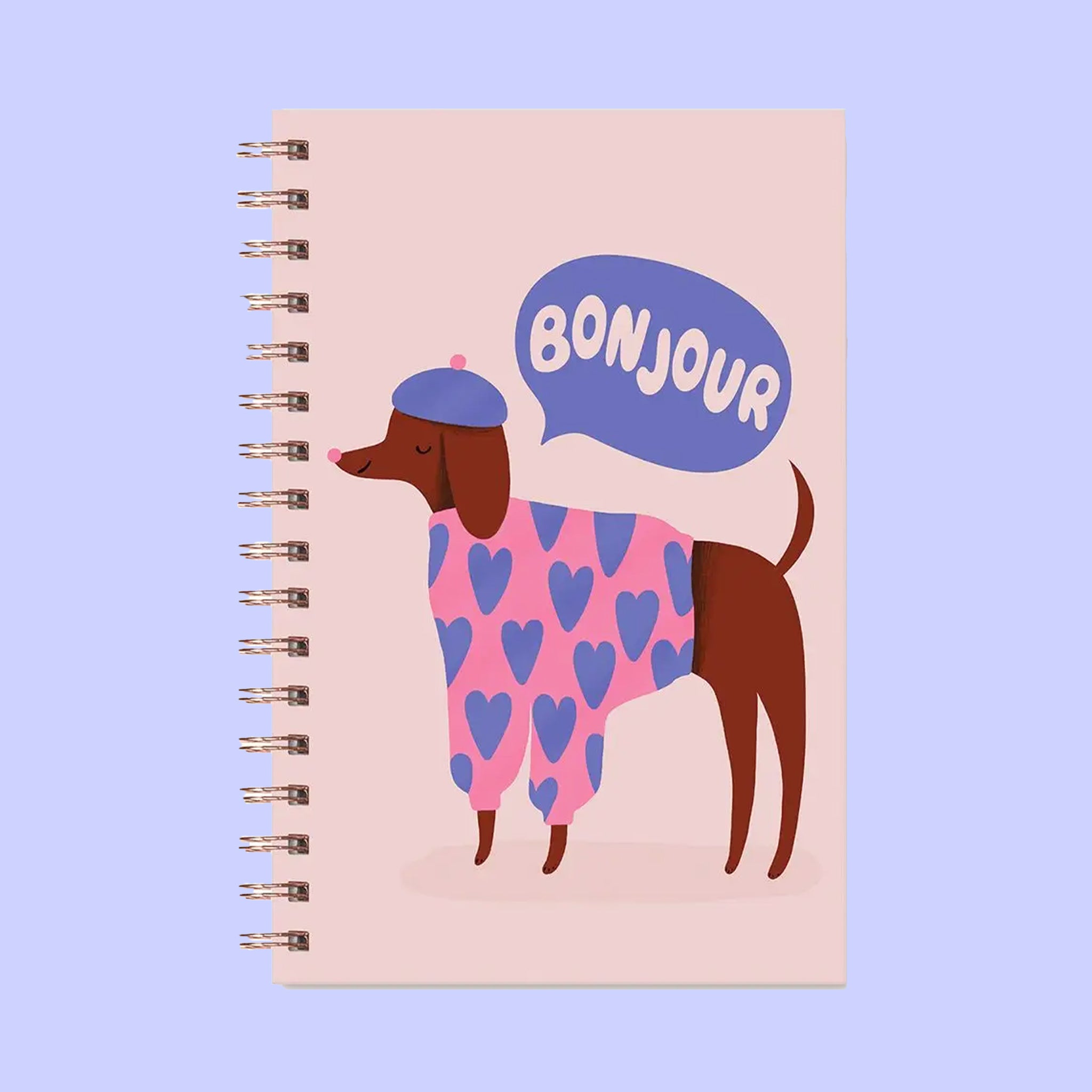 A light pink journal with an illustration of a dog wearing a beret and a speech bubble above that reads, &quot;Bonjour&quot;.