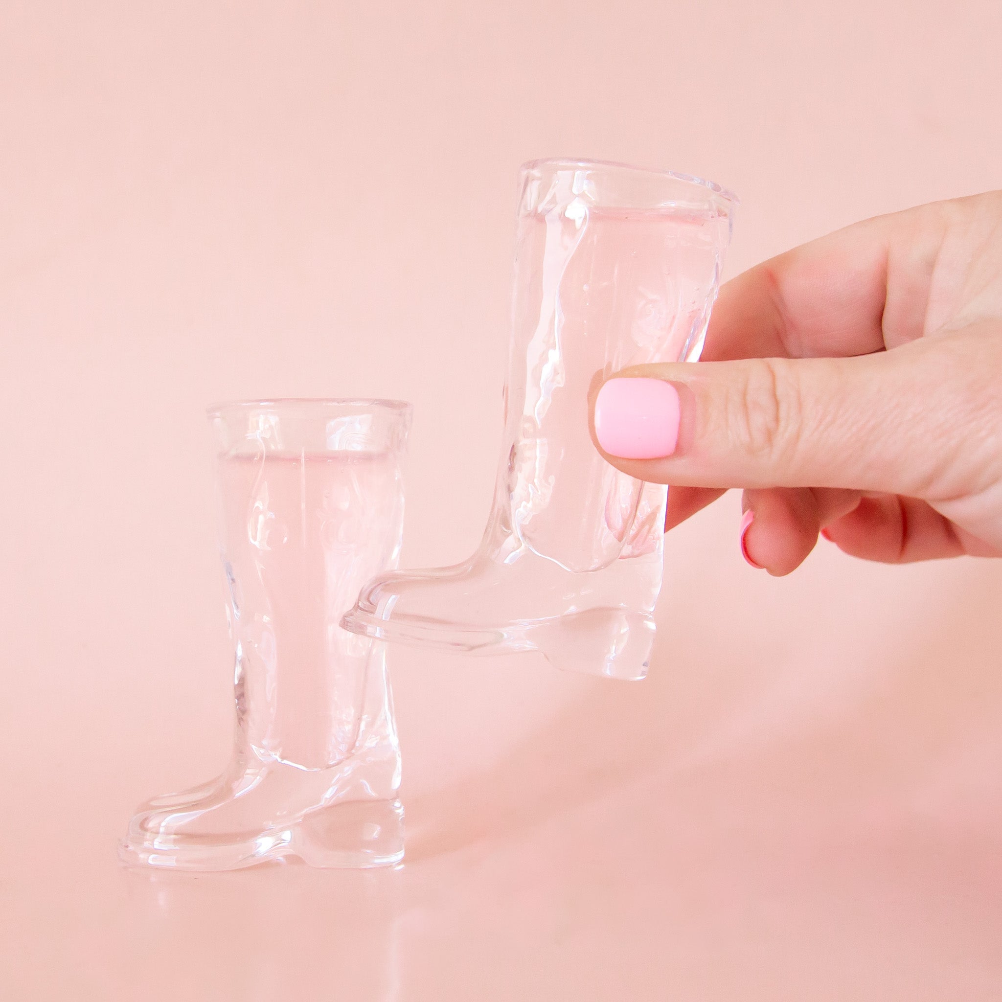 Two clear shot glasses in the shape of cowboy boots. 