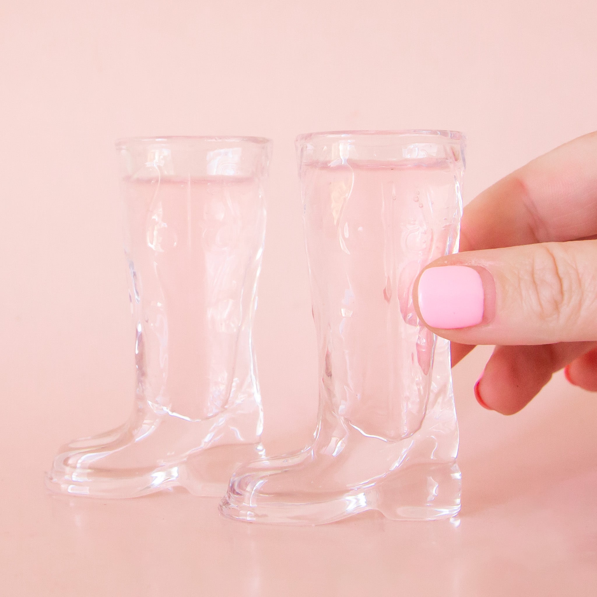 Two clear shot glasses in the shape of cowboy boots. 