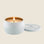 A white mini tin single wick candle with the name of the candle 'Voluspa Bourbon Vanille' on the lid. 