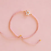 A pink and gold beaded bracelet with a opal flower design in the center. 