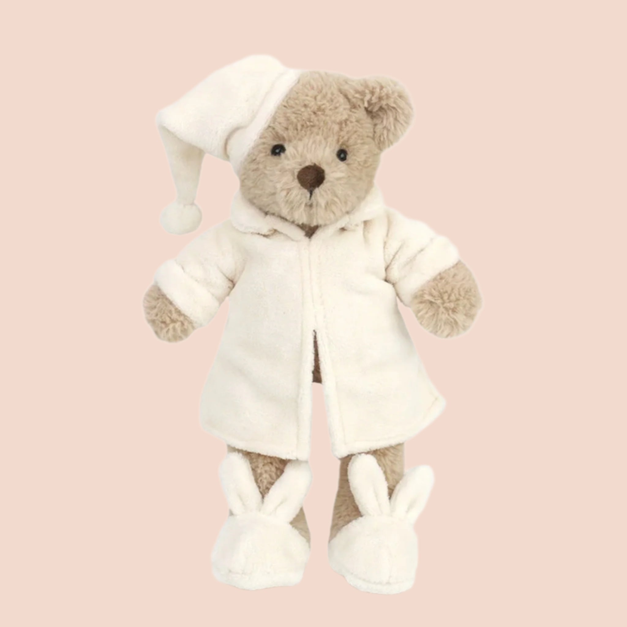 A bear stuffed animal wearing a white robe, night cap and bunny slippers. 