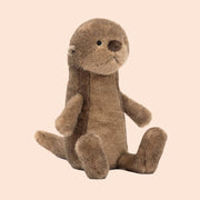 A brown otter shaped stuffed animal toy. 