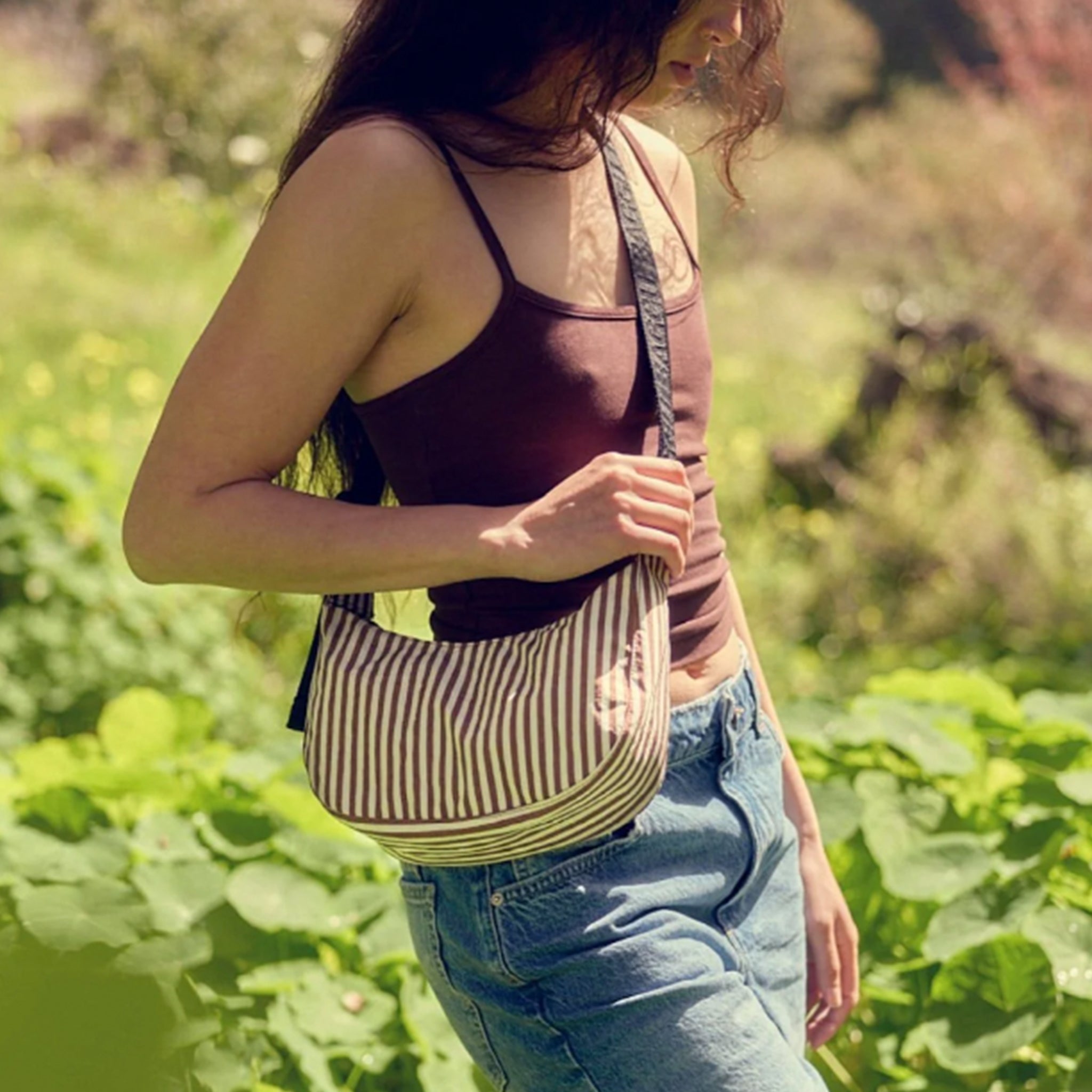 An ivory and browns striped nylon handbag with a black strap.