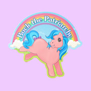 On a purple background is a multi colored pony sticker with a rainbow above with text that reads, "Buck the Patriarchy". 