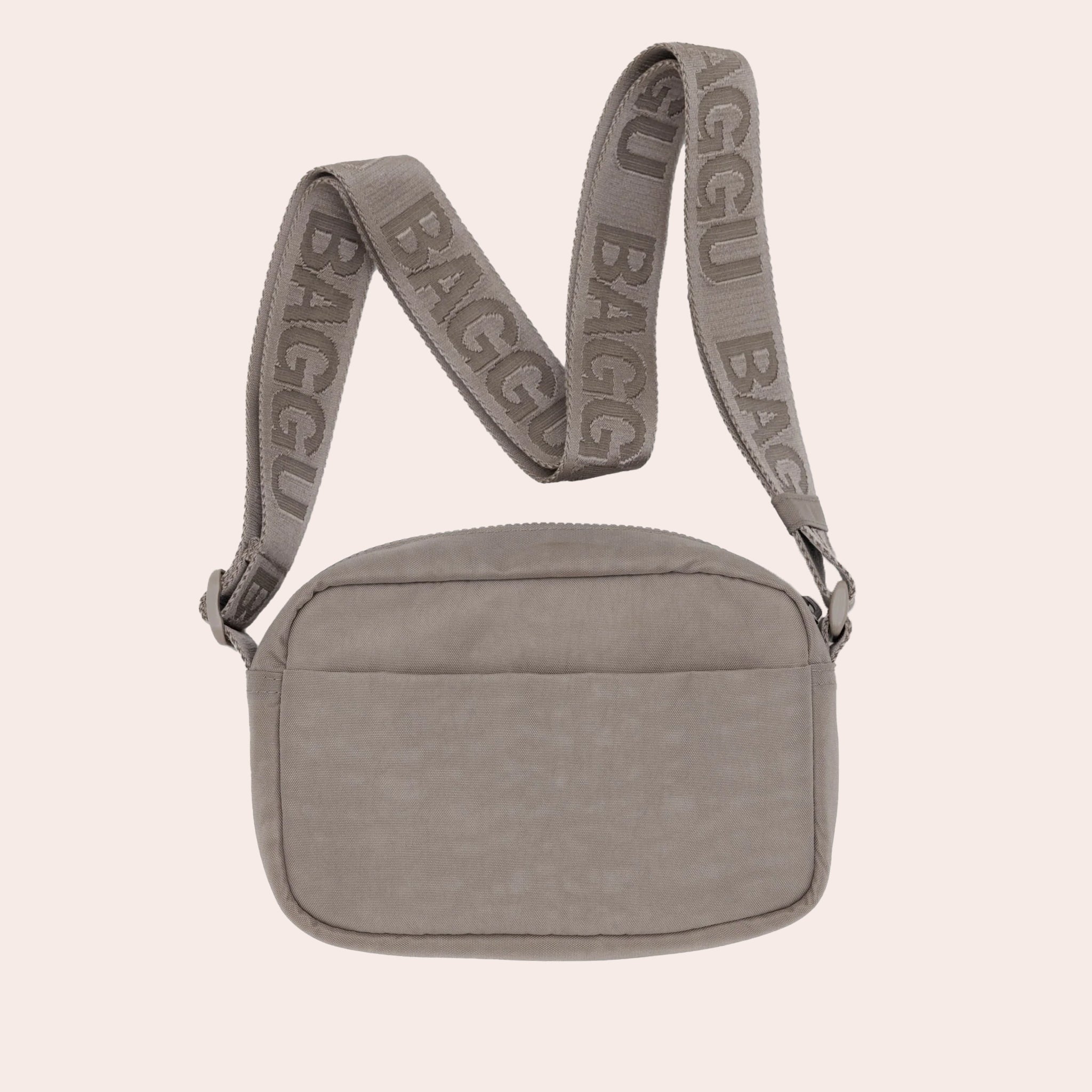 A tannish grey colored crossbody bag with an adjustable strap. 