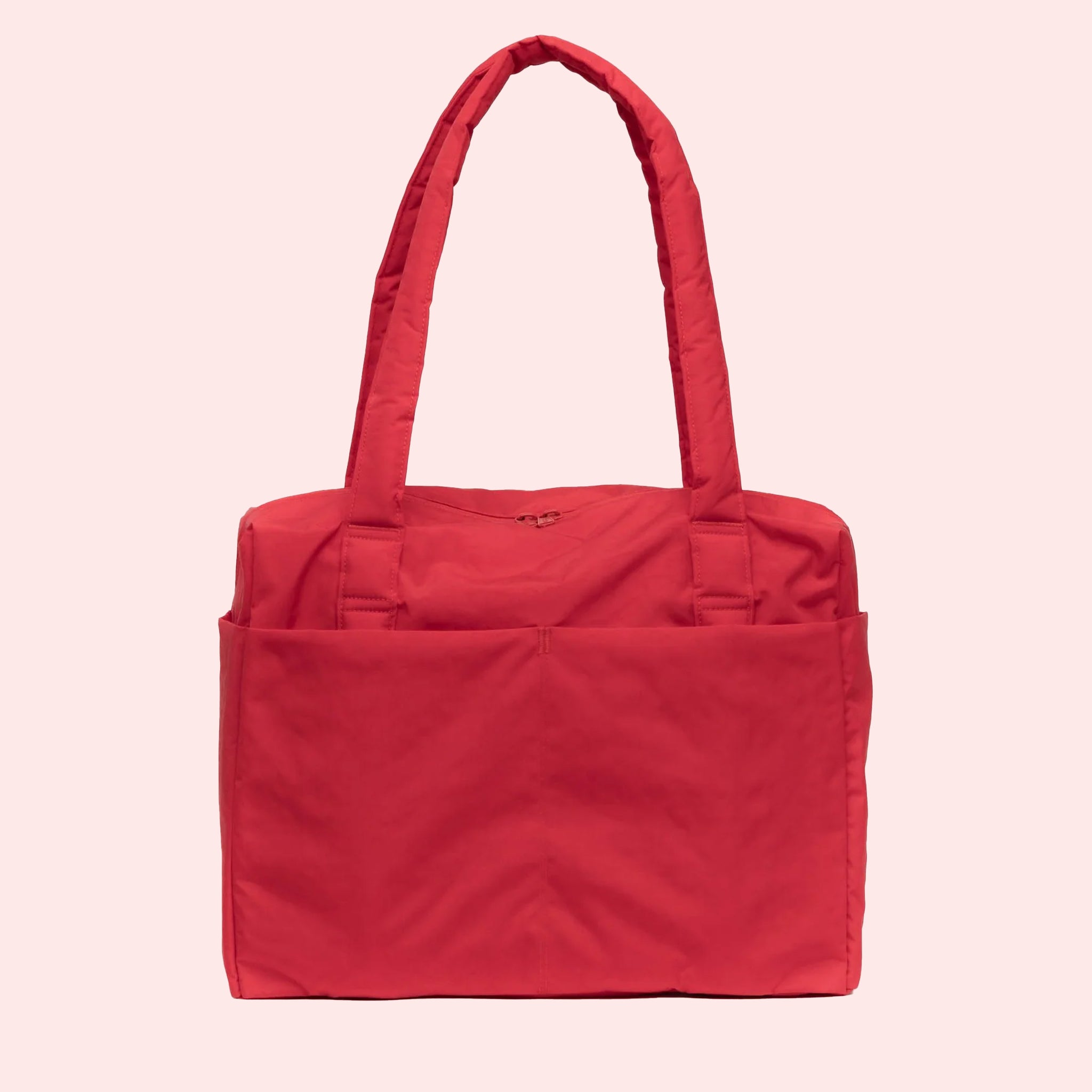 A red small carry on tote bag with two handle straps, front pockets and a zipper closure. 