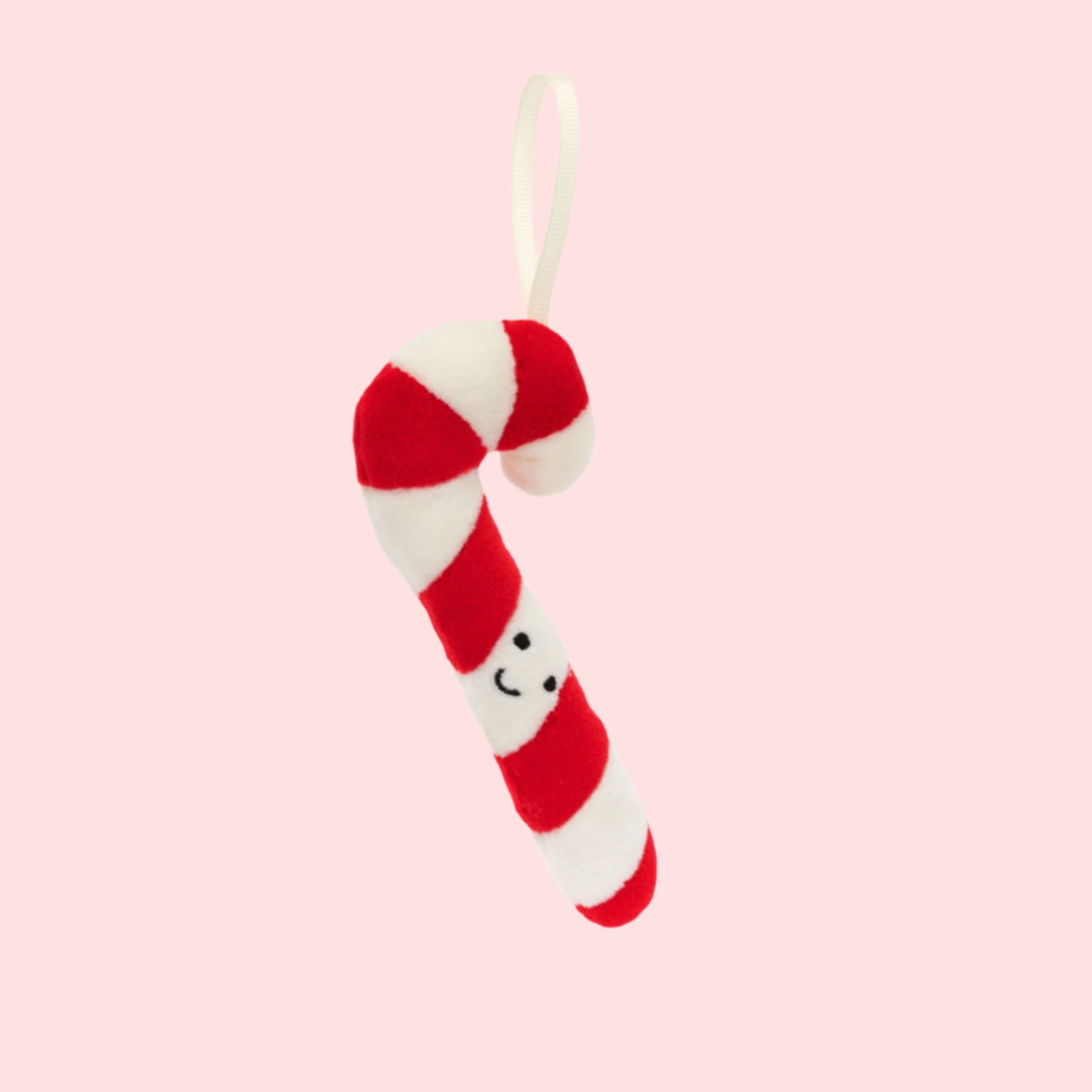 A red and white striped candy cane ornament with a smiling face. 