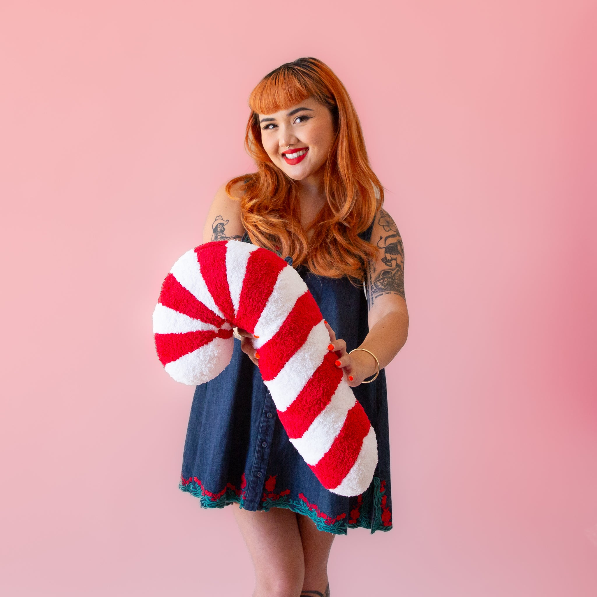 A red and white candy cane shaped pillow. 