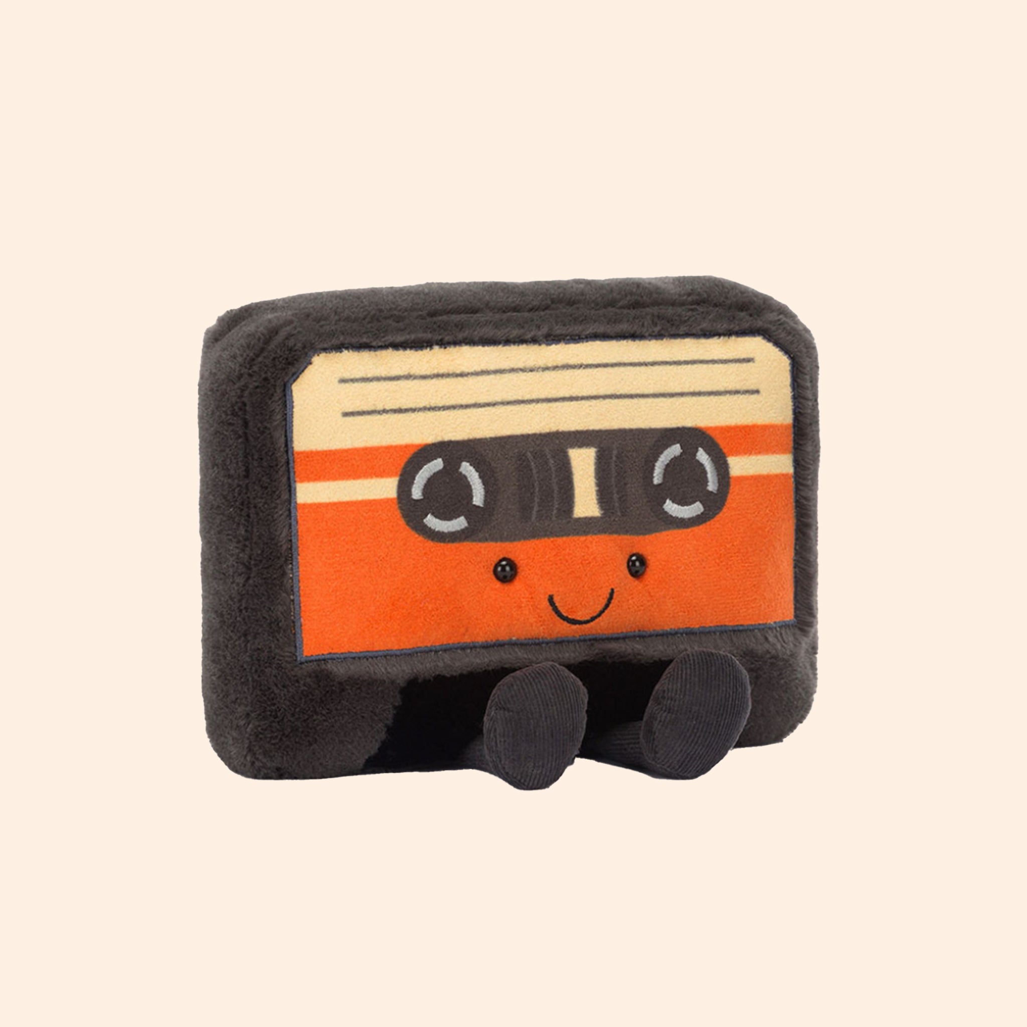 An orange, black and tan cassette tape shaped stuffed toy. 