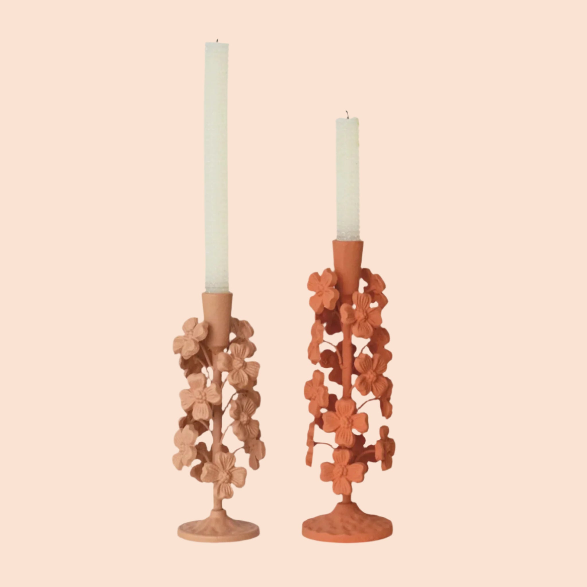 The two colors of the cast iron flower candle holders next to one another. 