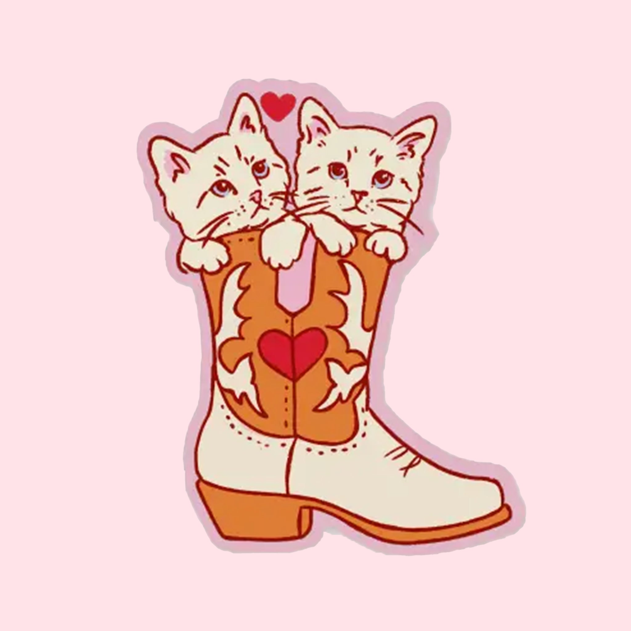 A vinyl sticker in the shape of two kittens sitting inside of a cowgirl boot that has a heart design on it. 