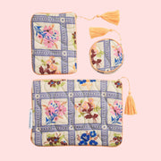 A set of three pouches with a floral print and a yellow string tassel. 